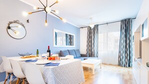 A modern living room with a dining area, a sofa, a coffee table, and a kitchen area. - Holiday Apartment Caracola with Balcony, Covered Terrace & Wi-Fi (Vinaròs)