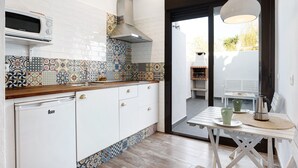 Een keuken met een magnetron, fornuis en witte kasten.