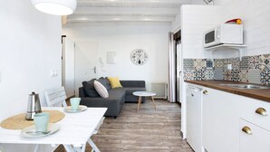 Een compacte woonruimte met een kitchenette, een eethoek en een bank.