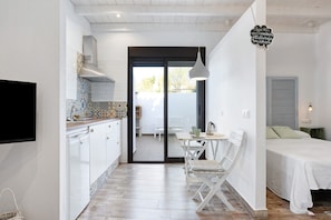 Una cocina moderna con armarios blancos, salpicadero de azulejos y un comedor con mesa y sillas blancas.