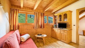 A wooden cabin interior with a sofa, a small table, a TV, and wooden cabinets. - 'Bolser Apartment Plan de Corones' with Mountain View, Garden & Wi-Fi (Pieve di Marebbe)