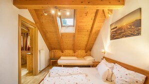 A bedroom with two beds, wooden ceiling beams, a skylight, and a painting of a sunset. - 'Bolser Apartment Plan de Corones' with Mountain View, Garden & Wi-Fi (Pieve di Marebbe)