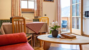Ein gemütliches Zimmer mit Esstisch, Stühlen, einer Couch und einem Blumentopf.