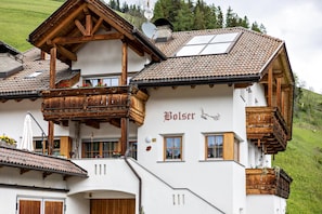 A traditional chalet with wooden balconies, a sloped roof, and a sign that reads 'Bolser.'