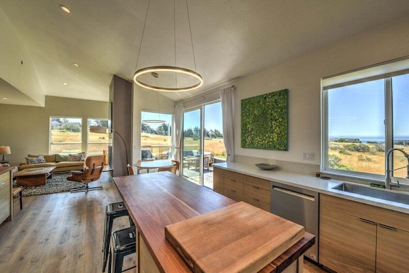 Una cocina moderna con encimera de madera, ventanas amplias y vistas al exterior.