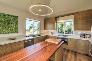 Una cocina moderna con armarios de madera, una isla central y ventanas amplias.