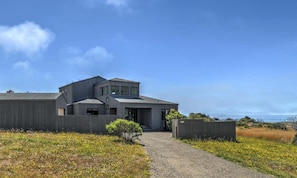 A modern two-story house with a gravel driveway leading to the entrance. - Lovely Day | BBQ Grill, Hot Tub, & Ocean Views (Sea Ranch)