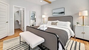 A modern bedroom with a bed, bedside tables, a bench, and a ceiling fan.