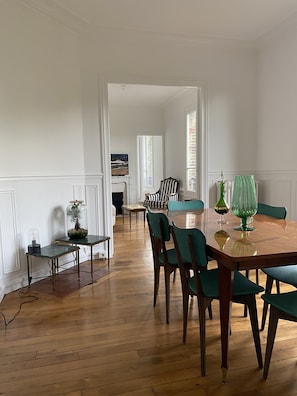 Cozy dining area with a wooden table and six chairs, fireplace, and large window.
