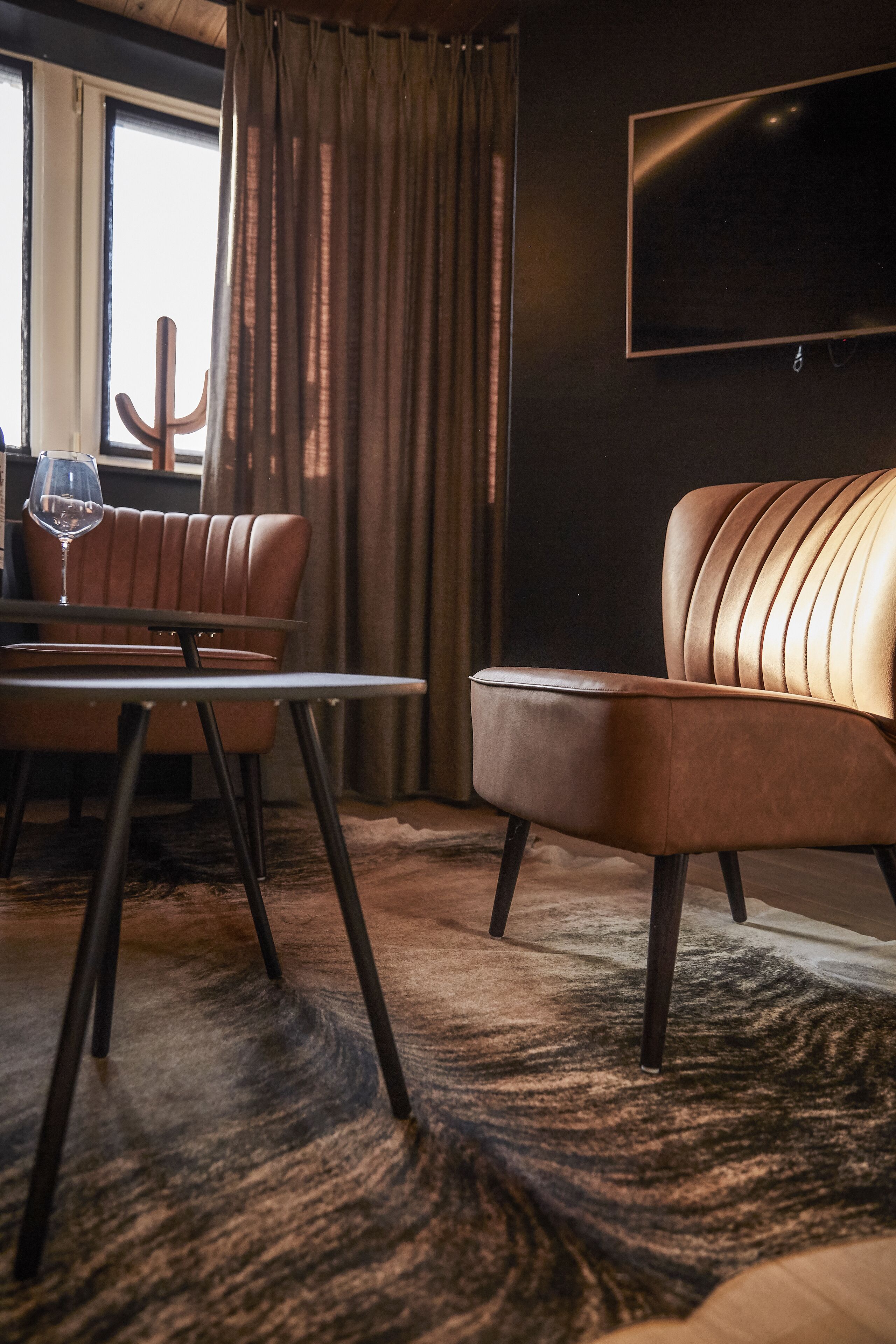 A modern living room with a leather sofa, a glass coffee table, and a patterned rug.