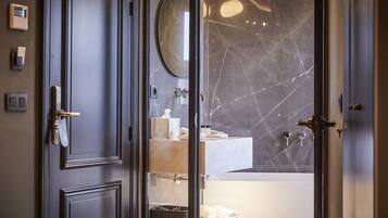Une salle de bain moderne avec un mur en marbre, un miroir rond et un porte-serviettes.
