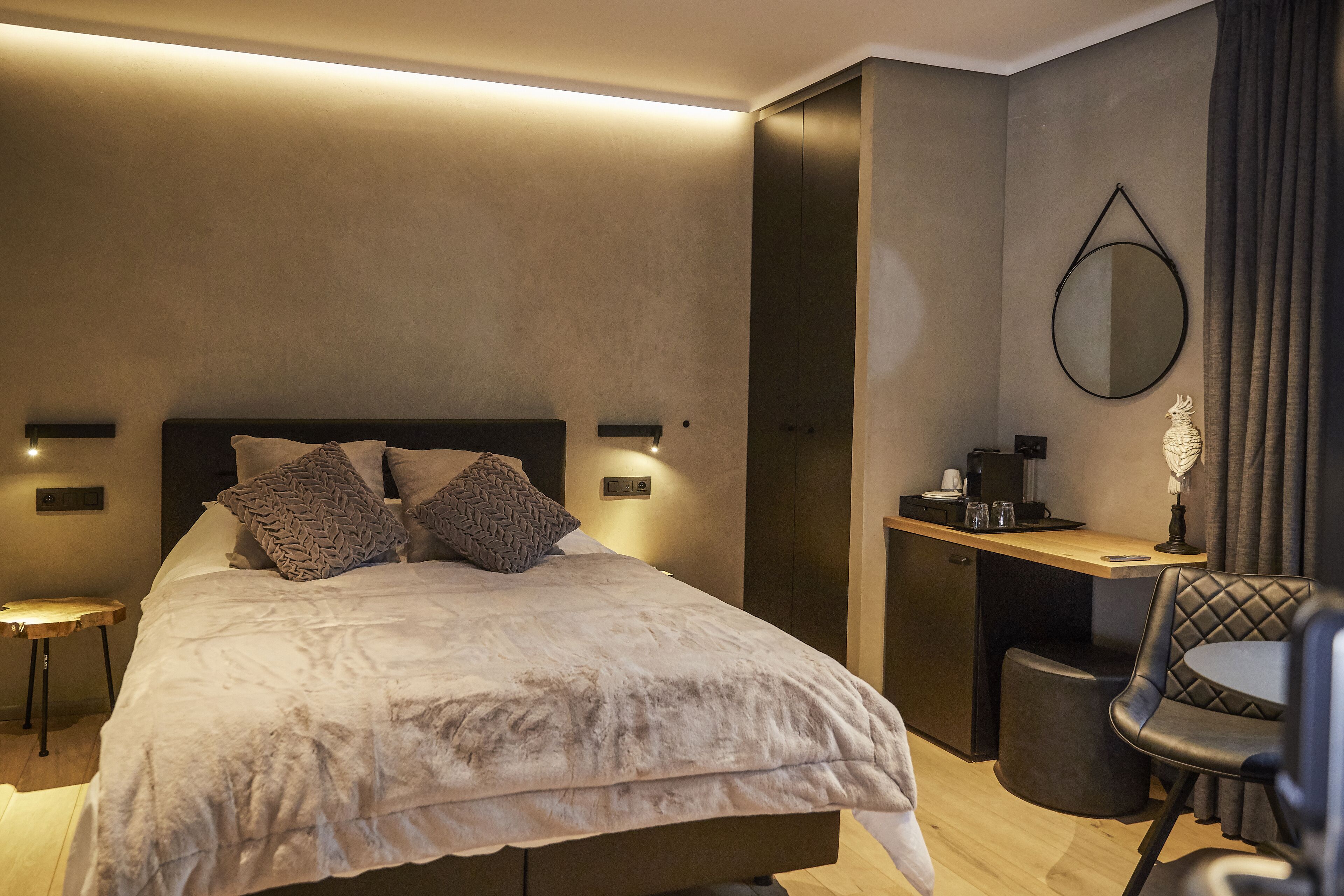 Una camera d'albergo moderna con un letto grande, comodini, una scrivania, una sedia e uno specchio.