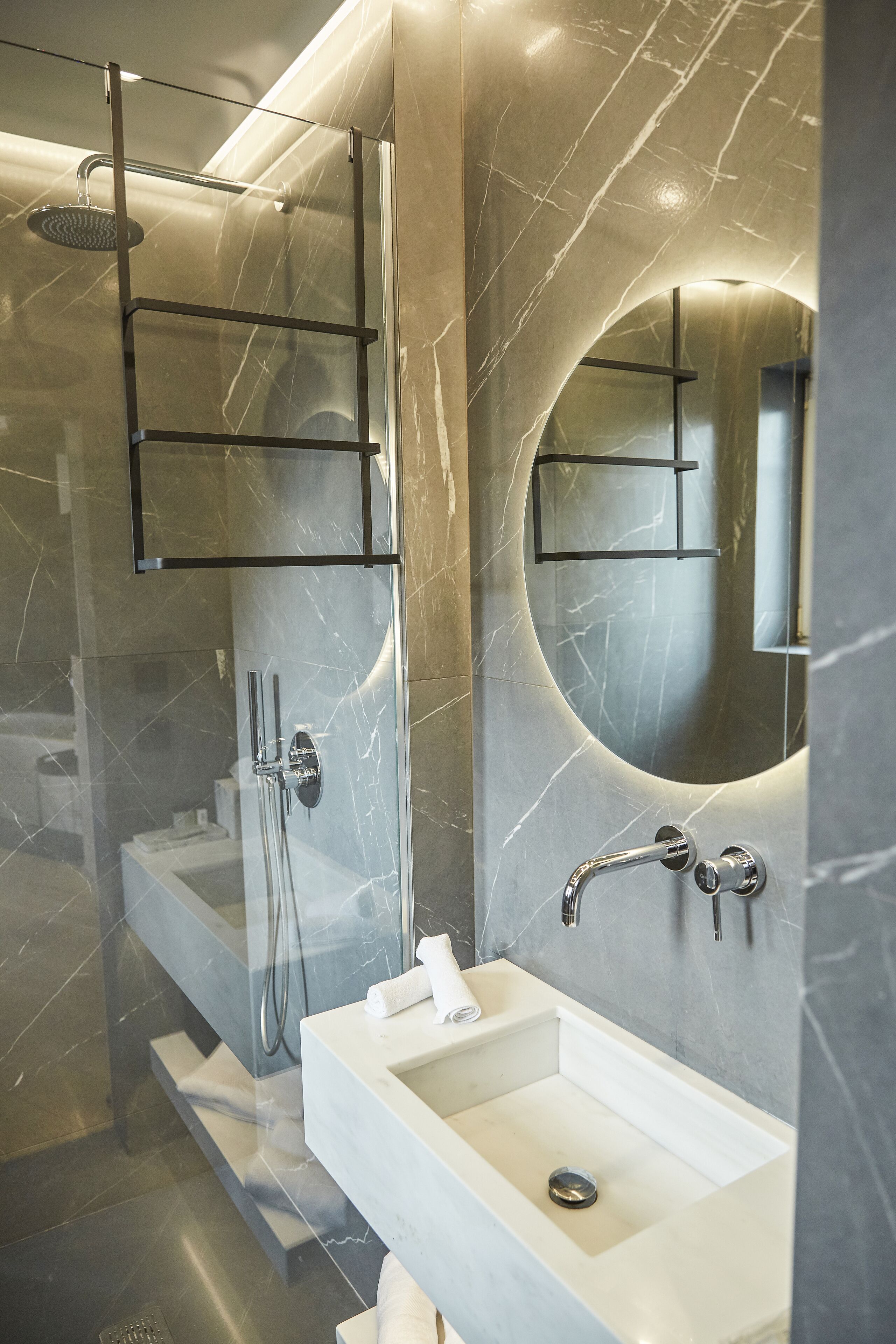 A modern bathroom with a glass-enclosed shower, a marble vanity, and a large mirror.