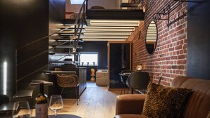 A modern interior with a staircase, a brick wall, and a leather sofa. - Hotel ONIRO - Luxury Rooms & Wellness Suites (Tournai)
