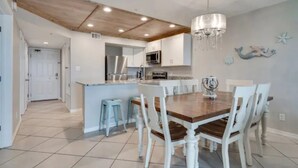 A kitchen with white cabinets, a wooden ceiling, and a chandelier.