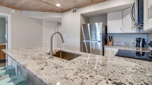 A kitchen with granite countertops, stainless steel appliances, and a wooden ceiling.