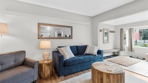 Un salon moderne avec un canapé bleu, un fauteuil gris et des tables d’appoint en bois.