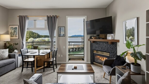 A modern living room with a fireplace, a dining area, and a view of a lake.