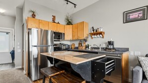 A modern kitchen with wooden cabinets, stainless steel appliances, and a central island with stools.