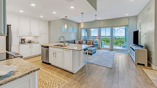 A spacious kitchen with white cabinetry, a large island, and a dining area with a view of the outdoors.