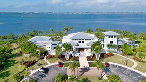 A large, modern hotel with multiple buildings, a parking lot, and a view of the ocean.