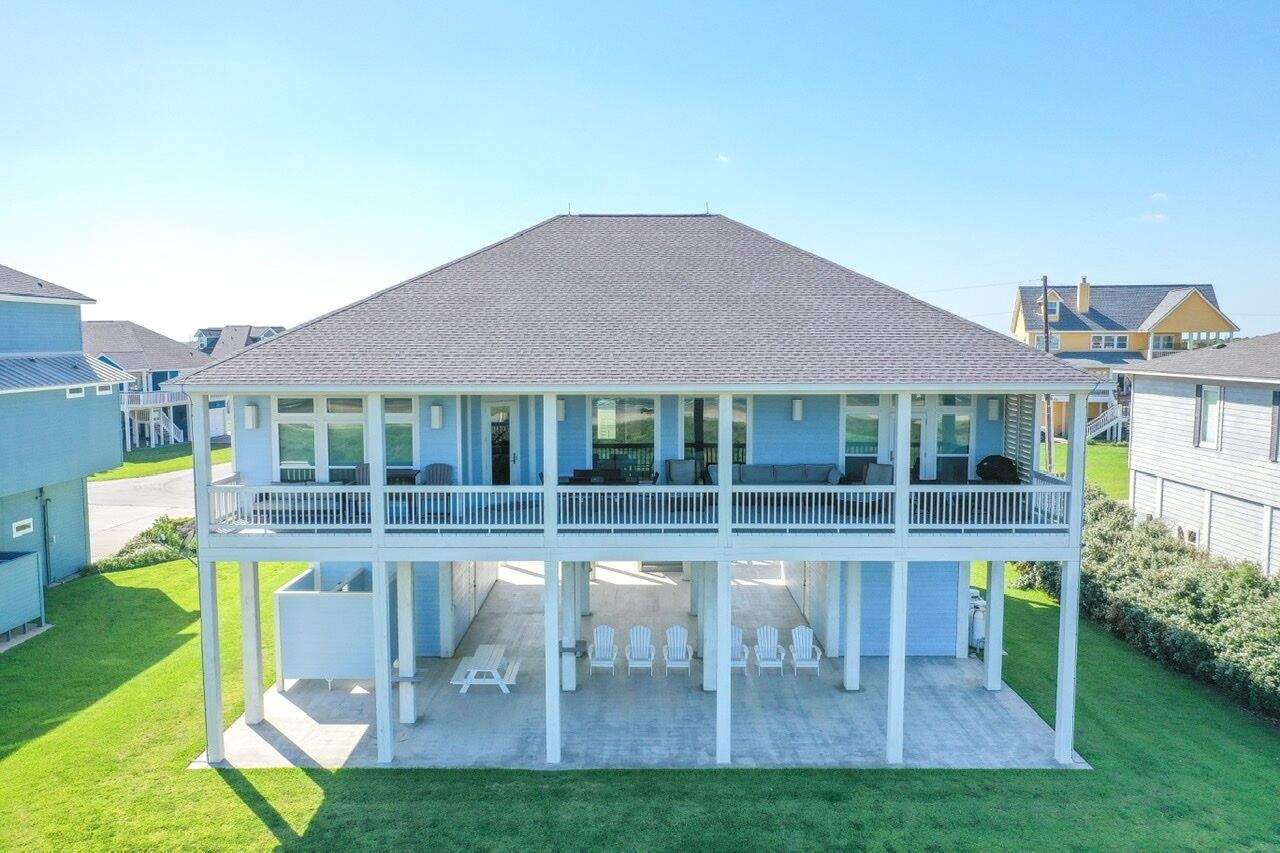 Une maison à deux étages avec un balcon, un patio couvert et une pelouse.