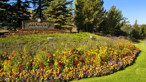 A sign for Arrowhead Country Club of the Rockies surrounded by a vibrant flower garden. - Aspenwood 311 2 Bedroom Condo by RedAwning (Edwards)