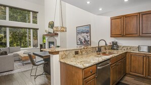 A modern kitchen with wooden cabinets, a granite countertop, and a built-in dishwasher. - Aspenwood 311 2 Bedroom Condo by RedAwning (Edwards)