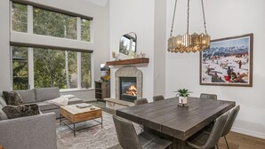 A spacious living room with a fireplace, large windows, and a dining area. - Aspenwood 311 2 Bedroom Condo by RedAwning (Edwards)