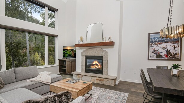 A modern living room with a fireplace, large windows, and a dining area. - Aspenwood 311 2 Bedroom Condo by RedAwning (Edwards)