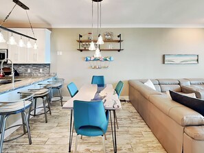 A modern kitchen with a dining area, a sofa, and a coffee table. - Atlantic Ocean by Tybee Vacation Rentals (Tybee Island)