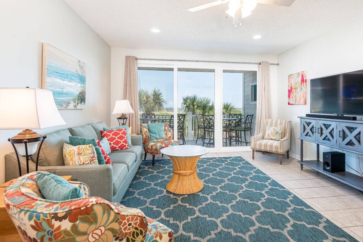 A spacious living room with a sofa, chairs, a coffee table, and a TV.