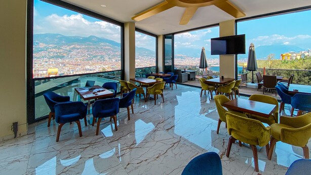 A modern dining area with a city view, large windows, and a ceiling fan. - Castle's Light Boutique Hotel (Alanya)