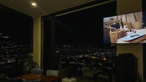 A modern living room with a large TV, comfortable seating, and a city view. - Castle's Light Boutique Hotel (Alanya)