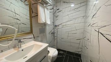 A bathroom with a white sink, a toilet, a shower, and a mirror with a gold frame.