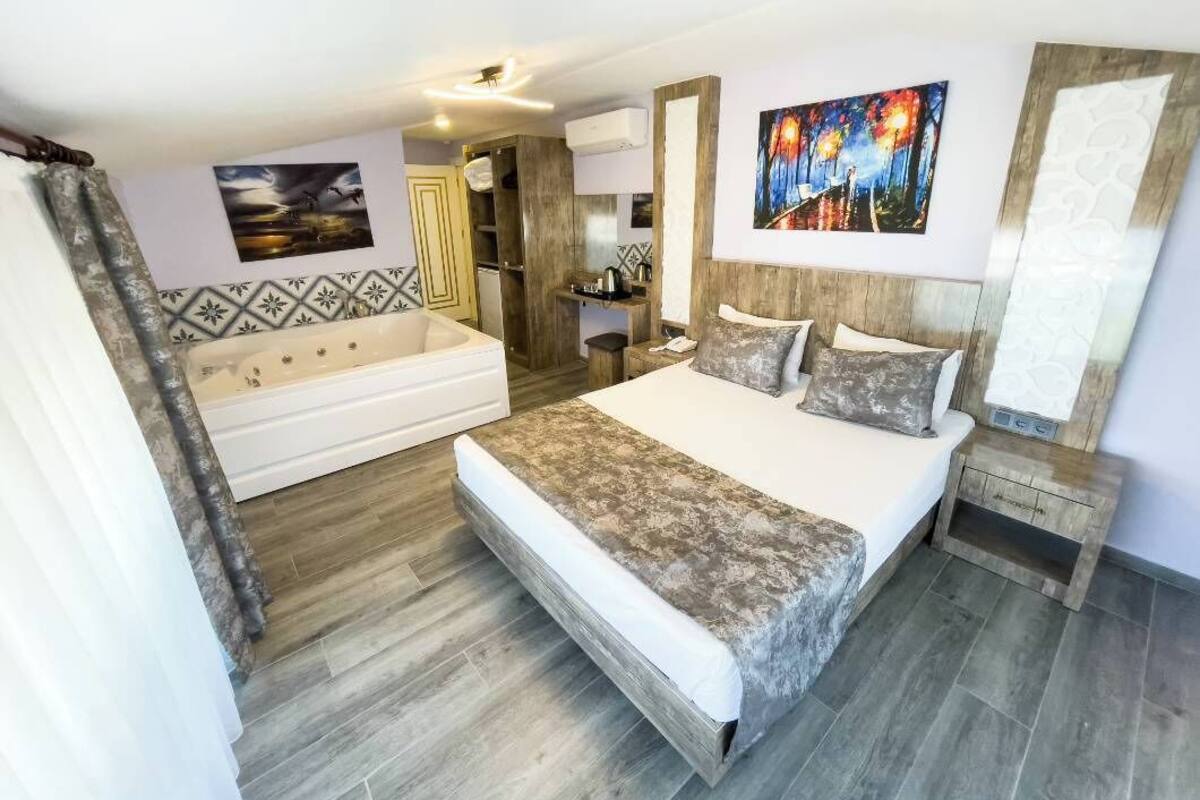 A bedroom with a bed, a sofa, a wooden cabinet, and artwork on the walls.