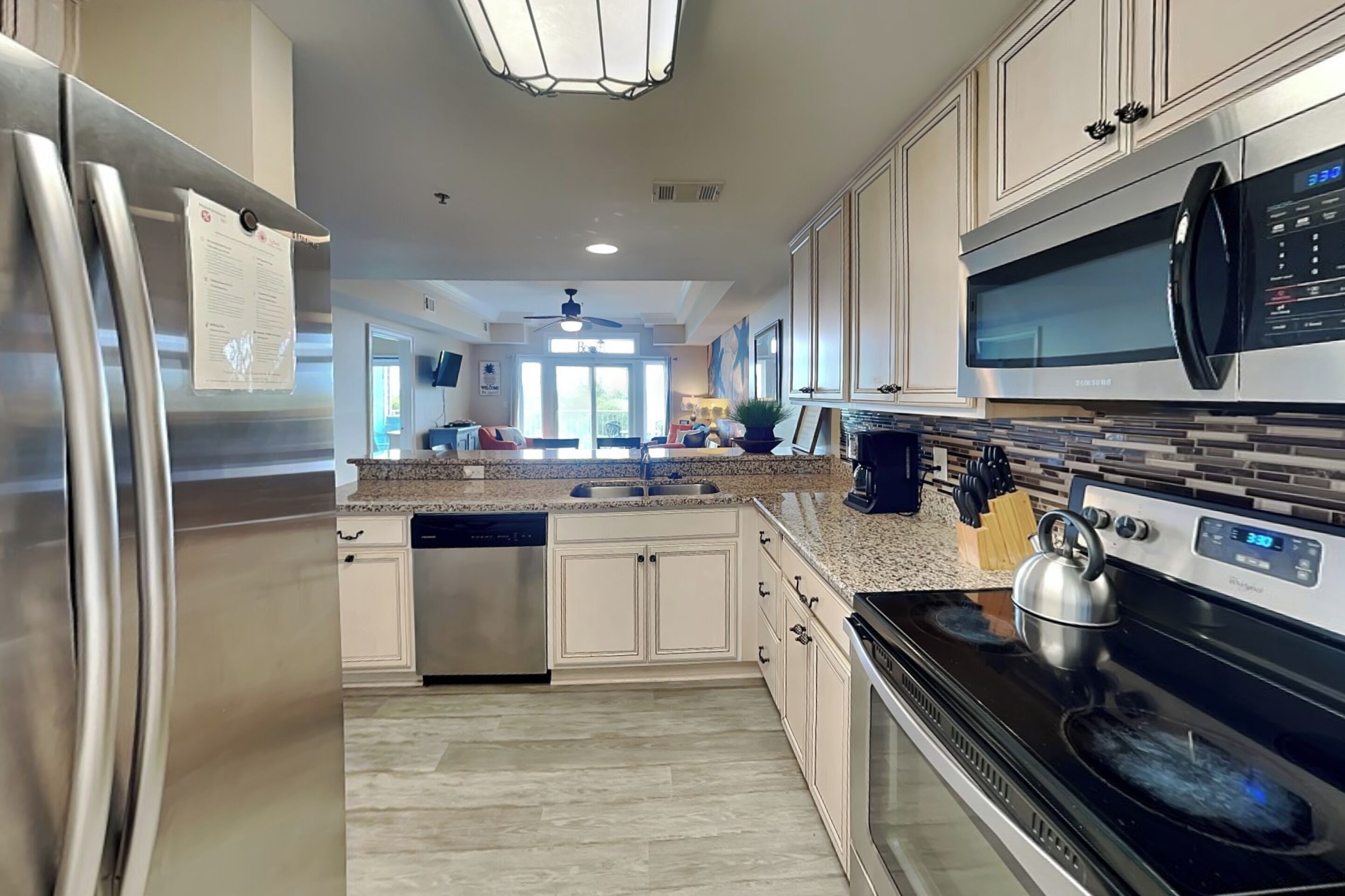 A modern kitchen with stainless steel appliances, a dishwasher, and a large island with seating.