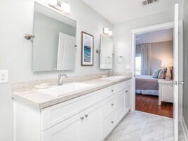 Une salle de bain moderne avec un double vasque, de grands miroirs et un dressing.
