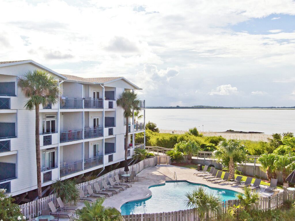 Un hotel con piscina, balcones y vistas al mar.