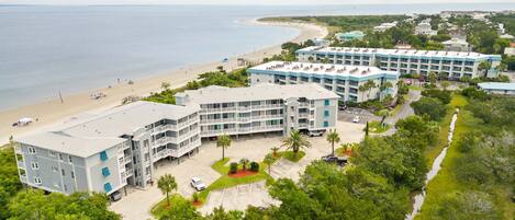 A coastal hotel with multiple buildings, a beach, and a clear view of the ocean.