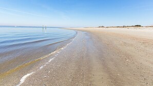 Une plage avec un ciel dégagé, une eau calme et un rivage sablonneux.