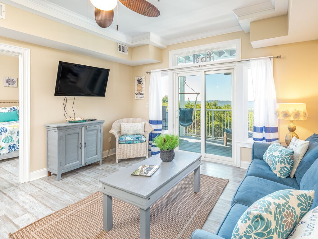 A living room with a sofa, a coffee table, a TV, and a sliding glass door leading to a balcony.