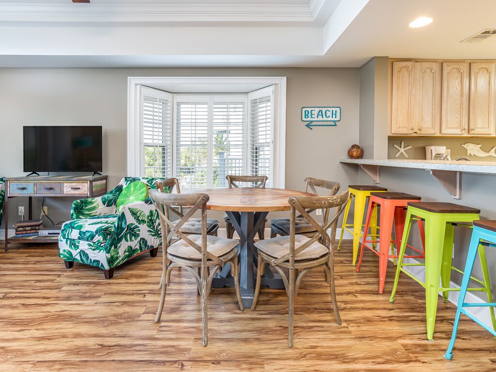 A dining area with a round table and chairs, a television, and a beach-themed sofa.