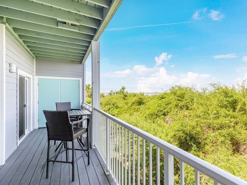 A covered outdoor area with a table and chairs, overlooking a dense green landscape.