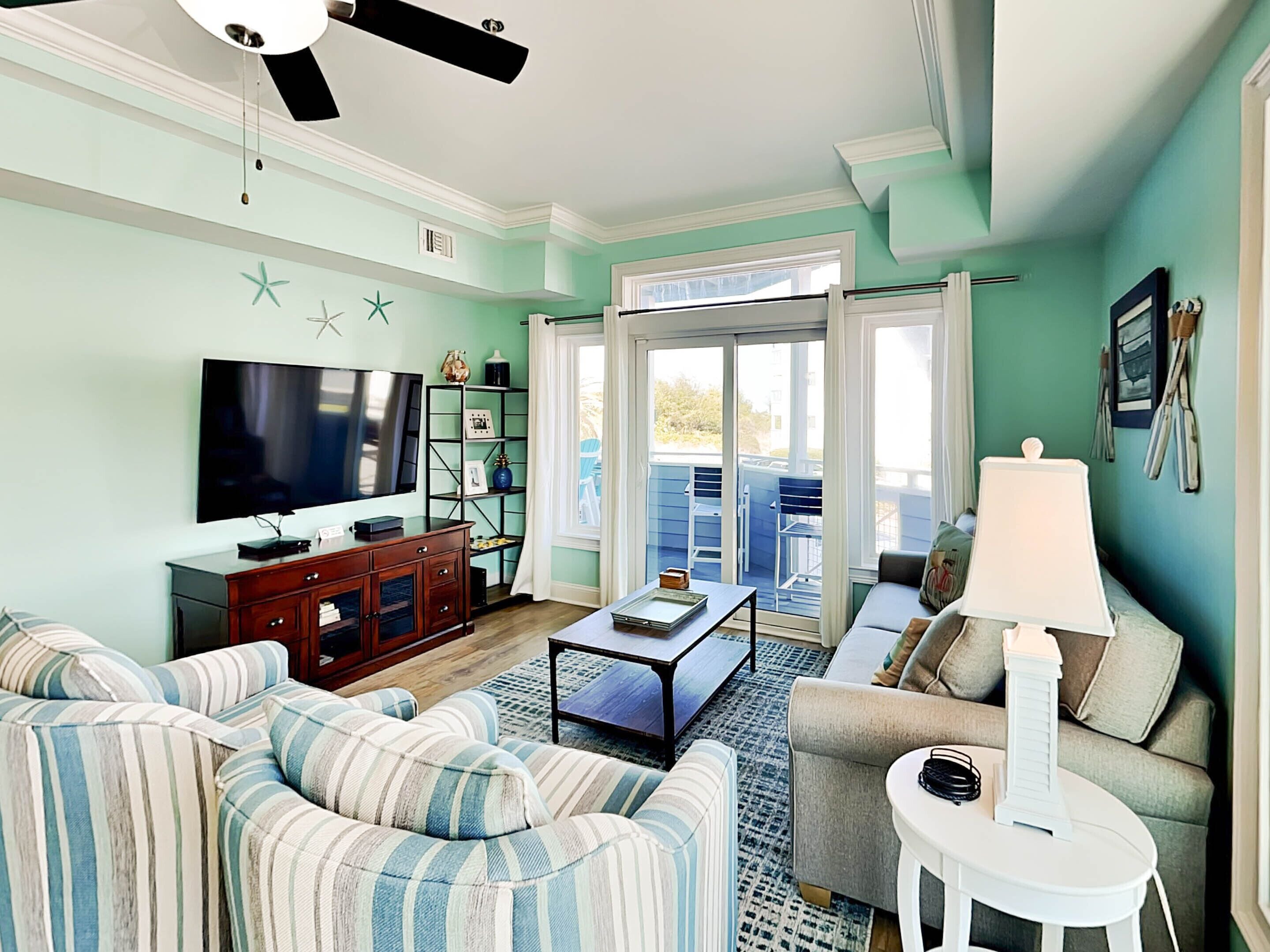 A living room with a television, sofa, coffee table, and a view of the outside balcony.