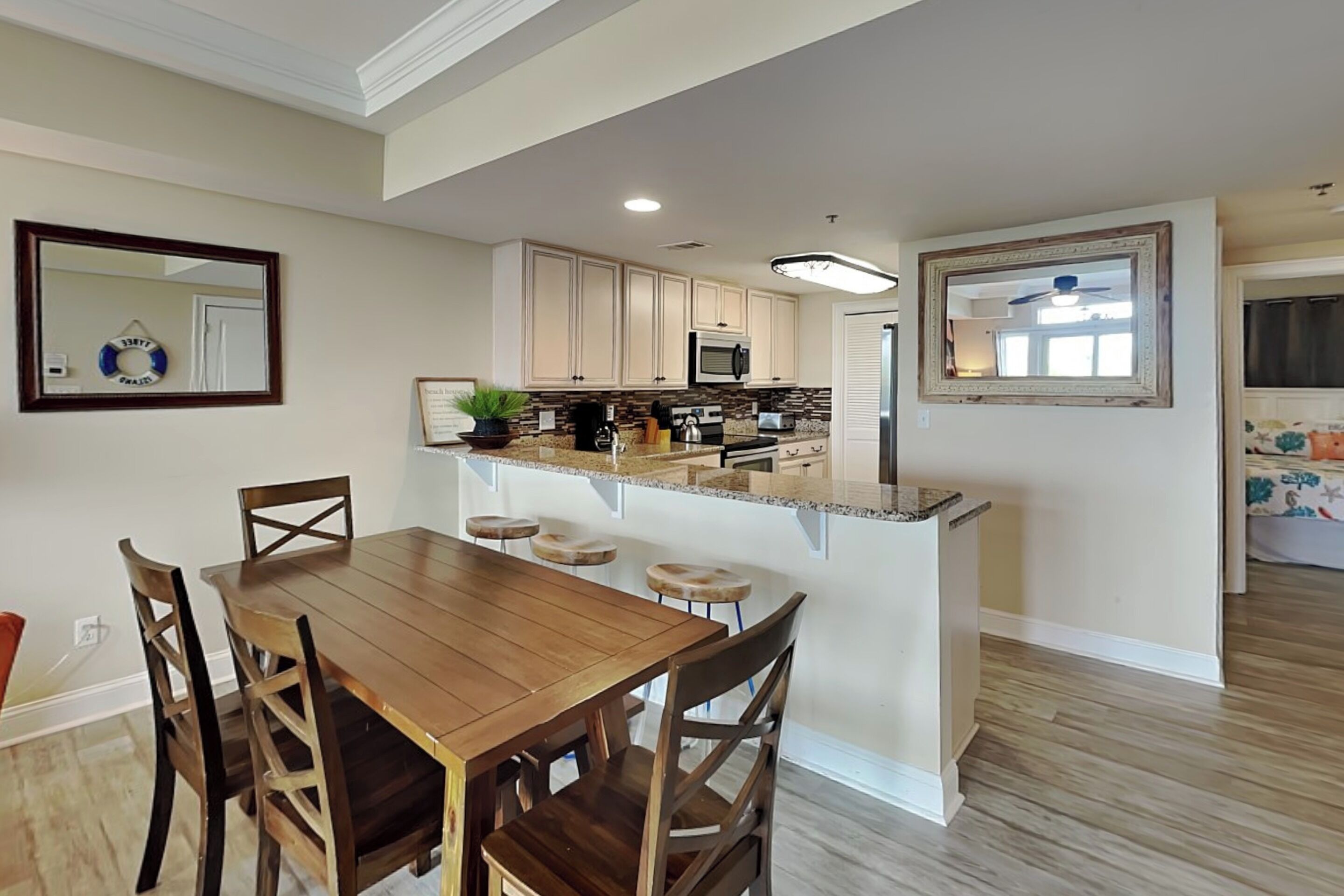 Una cocina con zona de comedor, sillas de madera, una isla de cocina y un microondas.