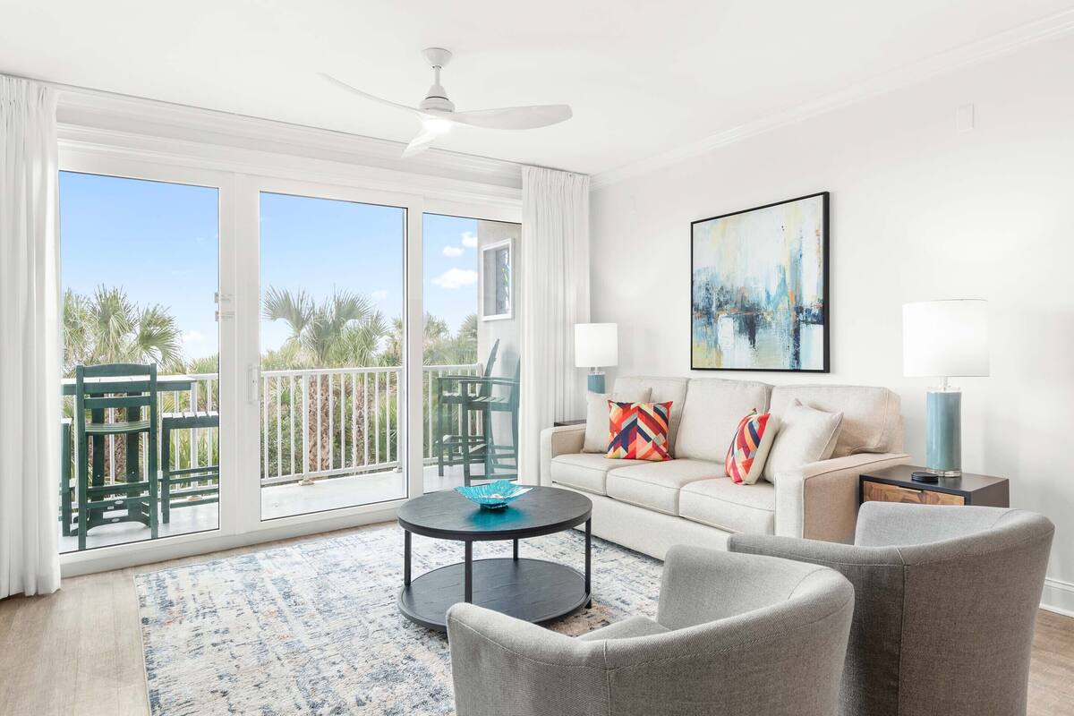 A modern living room with a sofa, two armchairs, a coffee table, and a painting on the wall.