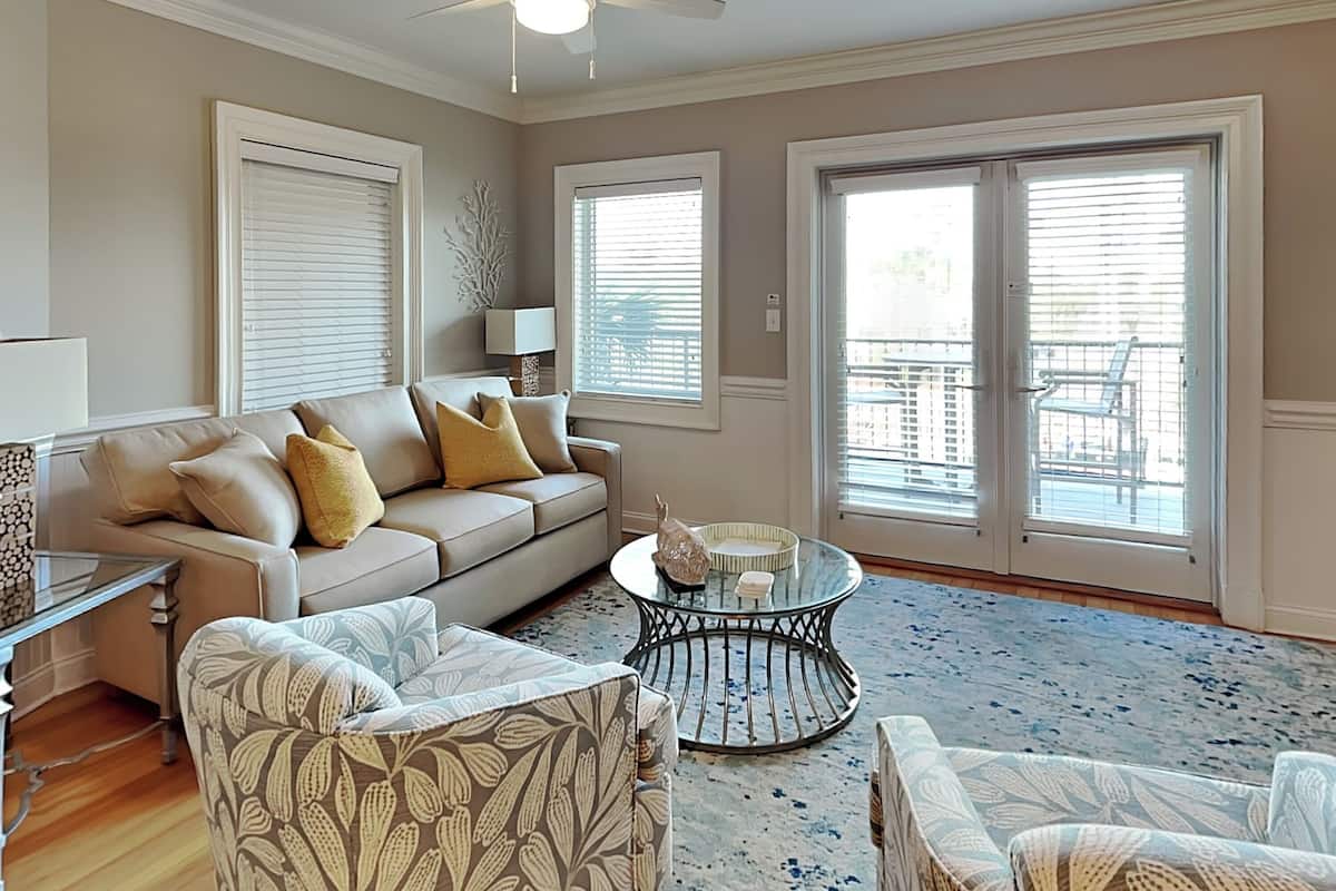 A living room with a sofa, armchairs, a coffee table, and a ceiling fan.