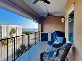 A balcony with wicker furniture, a ceiling fan, and a view of the ocean.