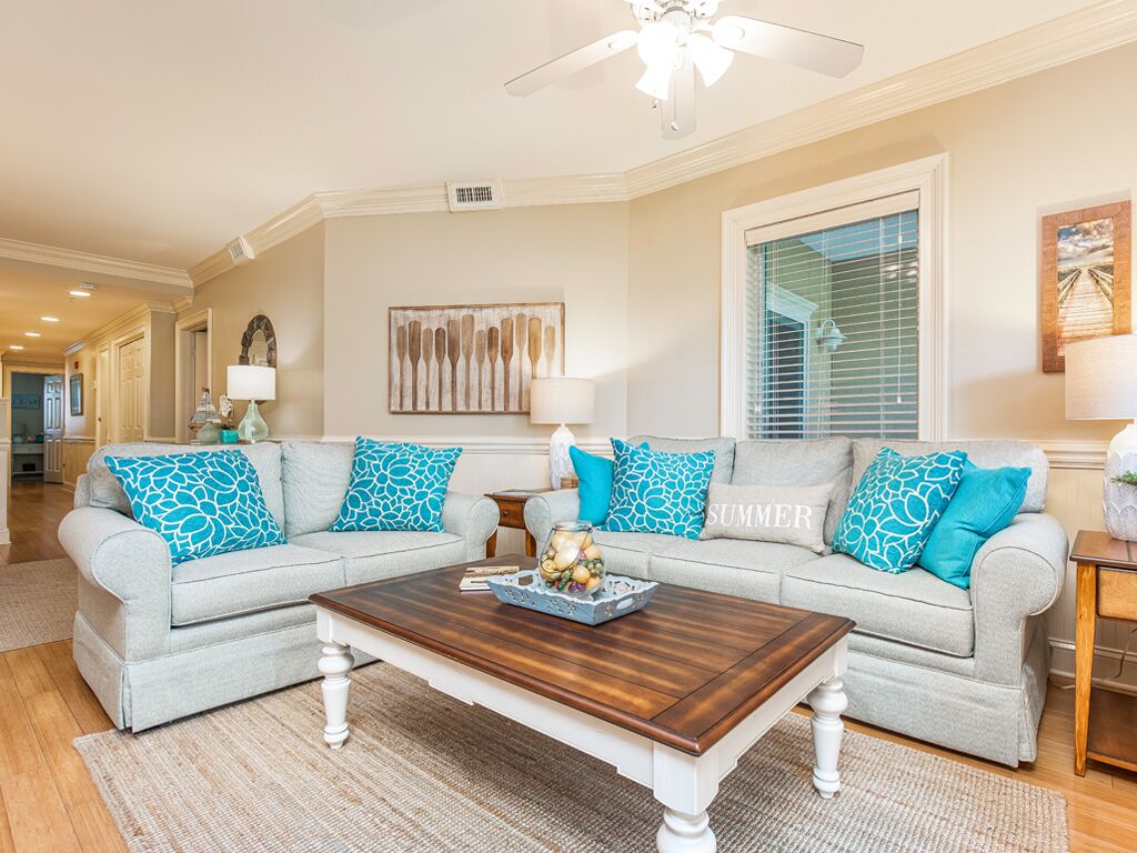 A living room with a grey sofa set, a wooden coffee table, and a ceiling fan.